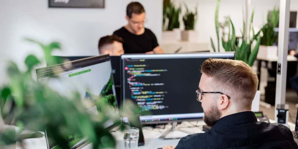 Webdesign und seine Psychologie Ein Mitarbeiter in einem Büro sitzt vor zwei Monitoren